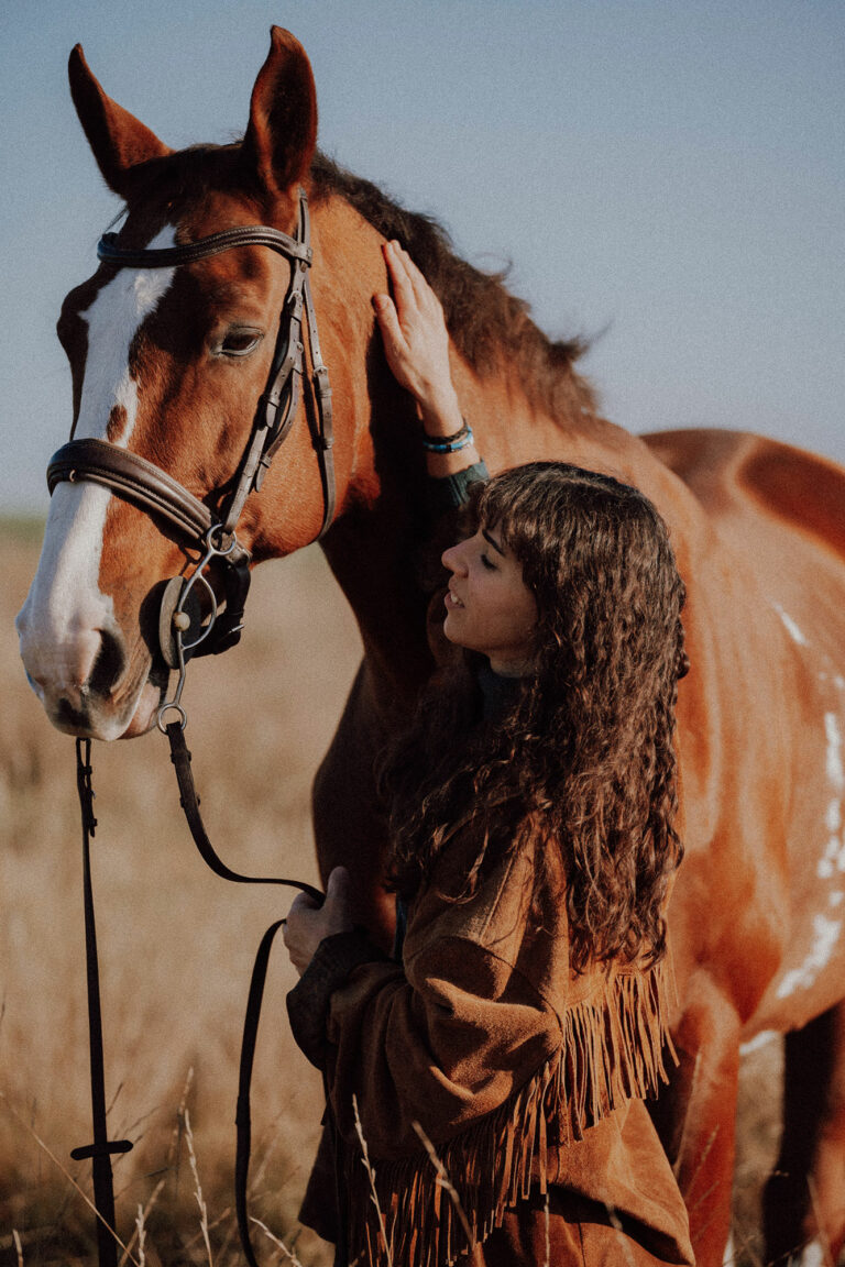 Cavalière qui caresse la tête de son cheval alezan à liste blanche, la joue contre son encolure